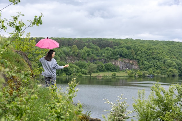 A woman walks under an umbrella in a mountainous area in cloudy weather