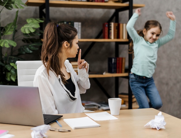 Foto gratuita donna che vuole lavorare in pace mentre sua figlia fa rumore