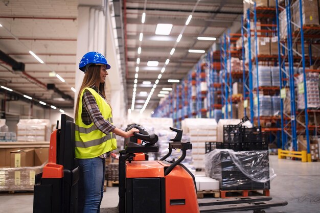 Woman warehouse worker operating forklift machine in large distribution warehouse center