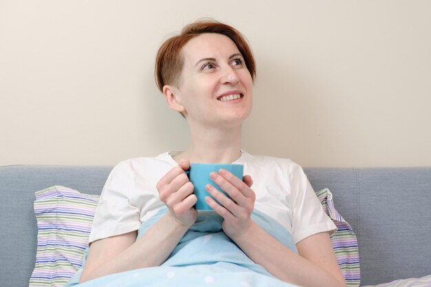 Woman was thinking about plans for the day, lying in bed with a mug of coffee