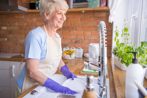 woman washing dishes in front of the window