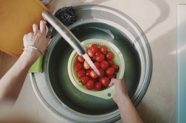 新鮮な野菜のトマトを洗う女