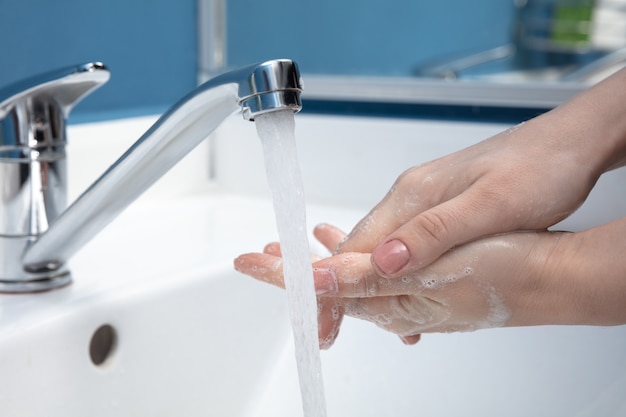 Женщина, мытье рук тщательно в ванной комнате крупным планом. Профилактика распространения инфекции и вируса гриппа