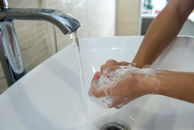 Женщина моет руки с дезинфицирующим мылом и водой в ванной после рабочего дня для гигиены и профилактики коронавируса.