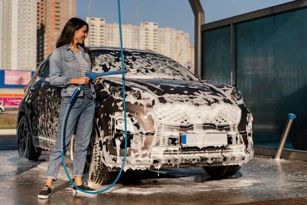 Женщина моет машину на улице
