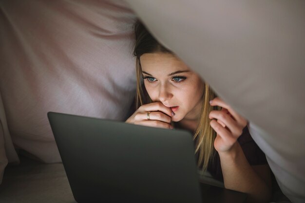 Woman watching film in blanket fort