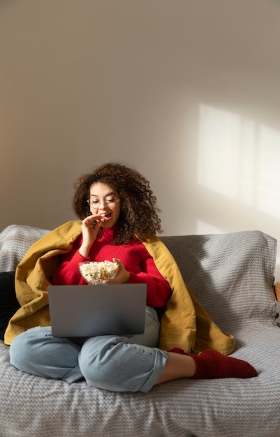 Foto gratuita donna che guarda film sul computer portatile a tutto campo