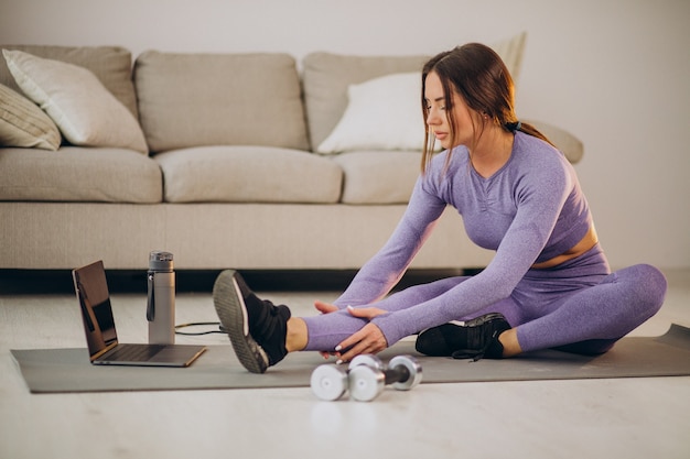 Foto gratuita donna che guarda tutorial e si allena da casa sul tappetino usando la corda per saltare e i manubri