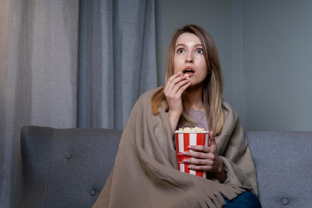 Foto gratuita donna che guarda la tv e mangia popcorn