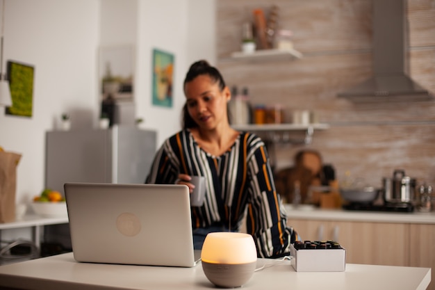 Woman watching video on laptop and realxing with essential oils aromatherapy from oil diffuser