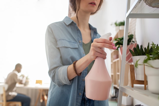 家で植物に水をまく女性