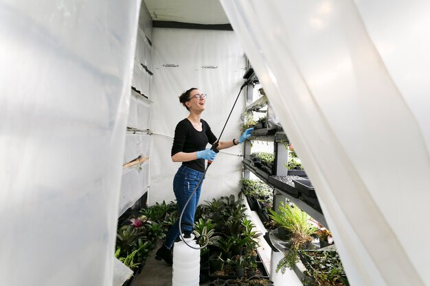 Woman watering plants in hothouse