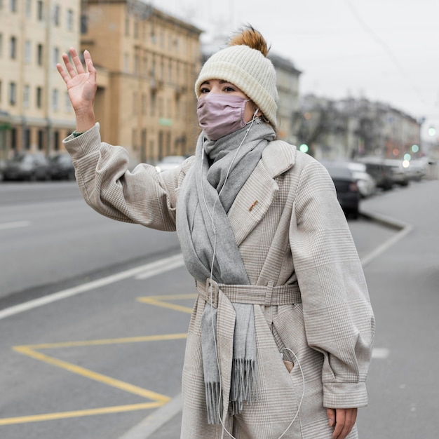 Бесплатное фото Женщина в медицинской маске машет рукой в городе