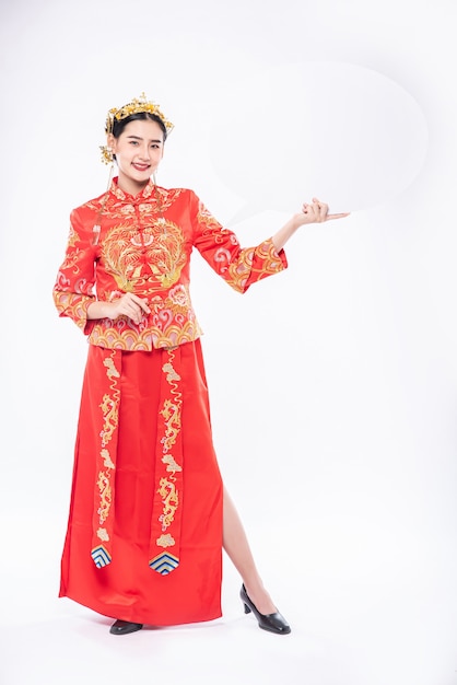 Женщина в костюме Cheongsam и черной обуви рада получить новые вещи для сюрпризов в китайском новом году