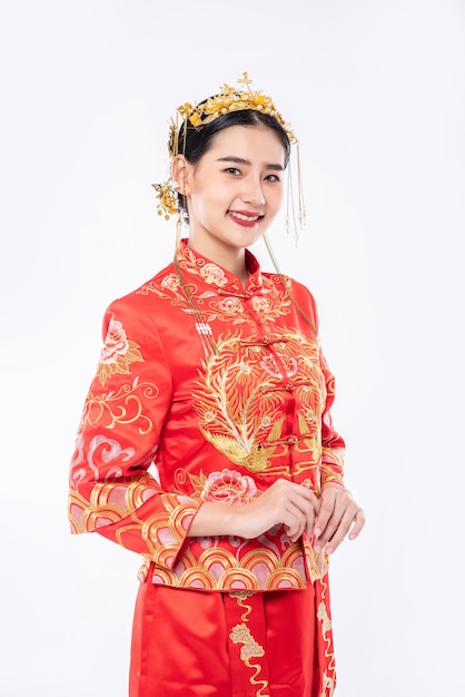 女性は中国の旧正月で買い物をする旅行者を歓迎するためにチャイナドレスの笑顔を着ています