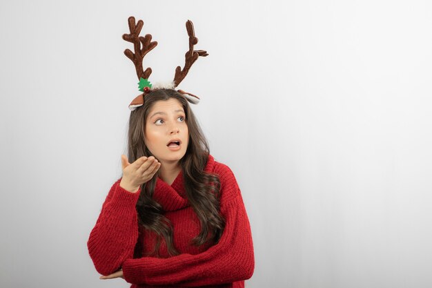 Woman wearing antler deer headband and looking up . 