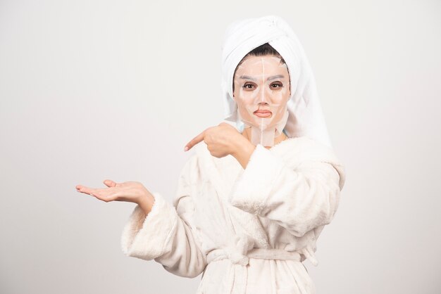 Woman wearing bathrobe and towel with facemask.