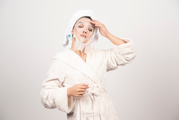 Free photo woman wearing bathrobe and towel with facemask.