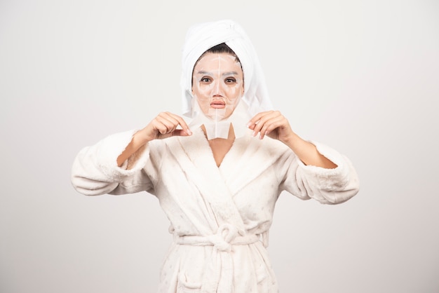 Woman wearing bathrobe and towel with facemask