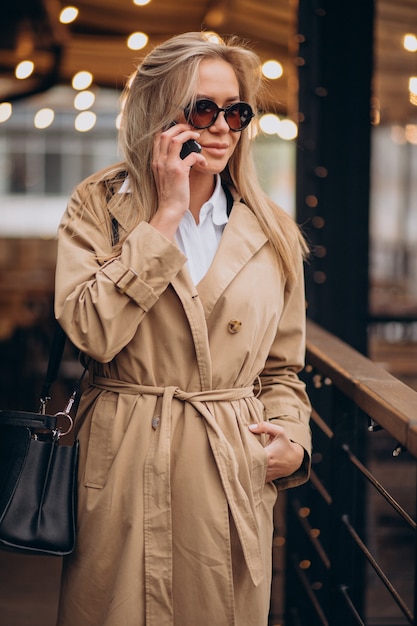 Woman wearing beige coat and walking in the street on Christmas