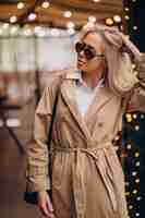 Free photo woman wearing beige coat and walking in the street on christmas