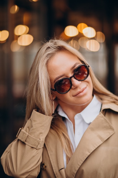 Free photo woman wearing beige coat and walking in the street on christmas