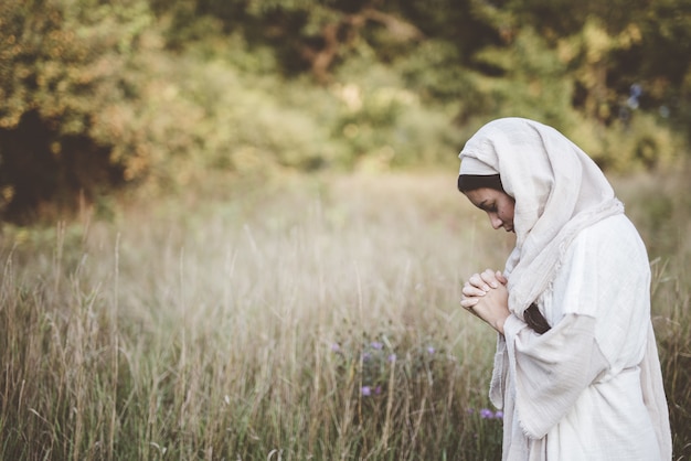 聖書のローブを着て、目を閉じて祈る女性
