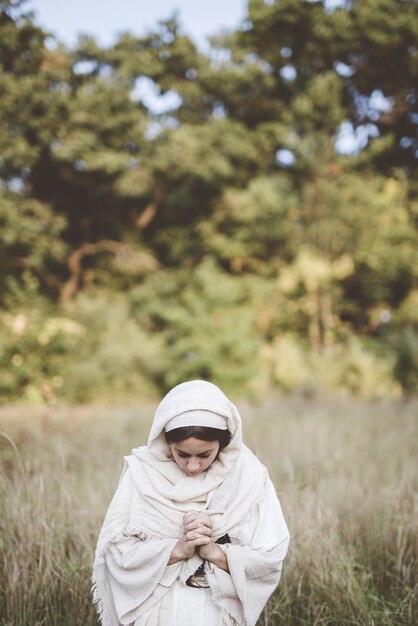 Woman wearing a biblical robe and praying while looking down