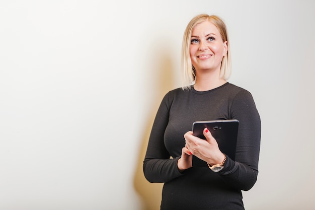 Free photo woman wearing black dress holding tablet smiling