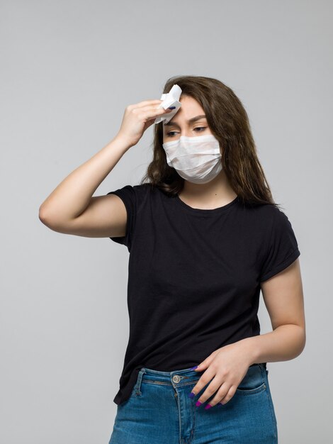 Woman wearing black t-shirt and medical protective mask feeling sick