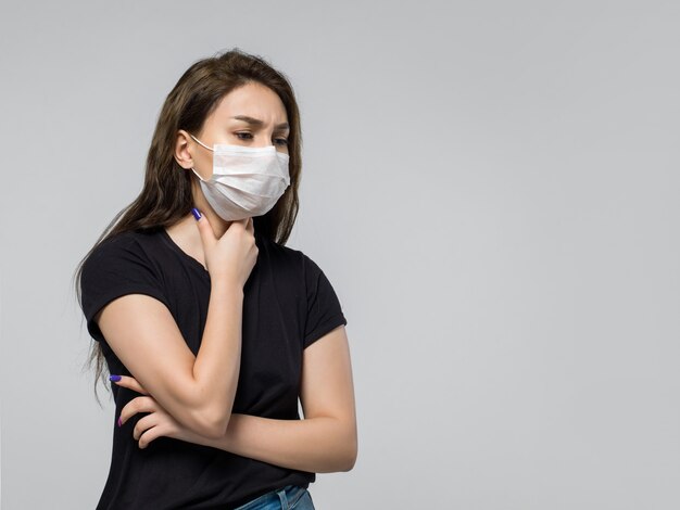 Woman wearing black t-shirt and medical protective mask feeling sick