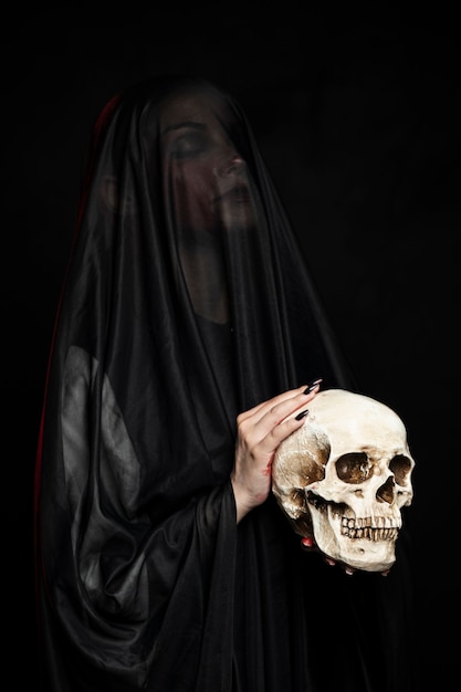 Woman wearing black veil and holding skull