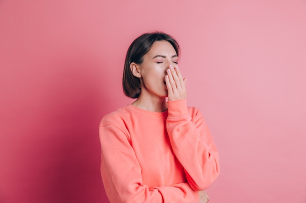 Woman wearing casual sweater on background bored yawning tired covering mouth with hand. Restless and sleepiness