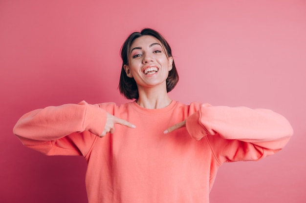 Woman wearing casual sweater on background pointing on herself with fingers, smiling positive and cheerful