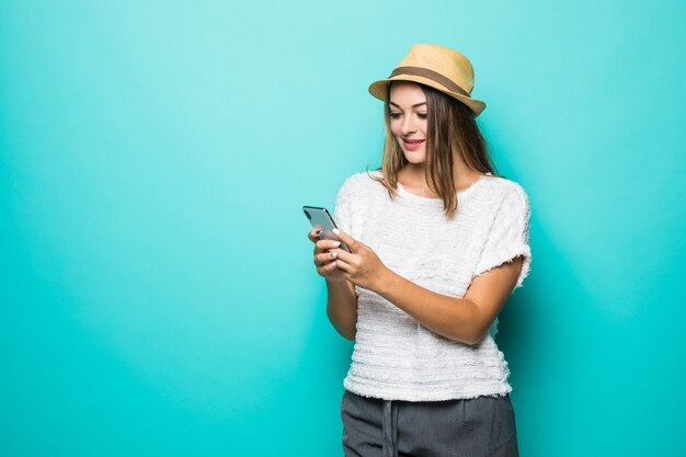 Woman wearing casual white shirt and hat using smartphone on blue