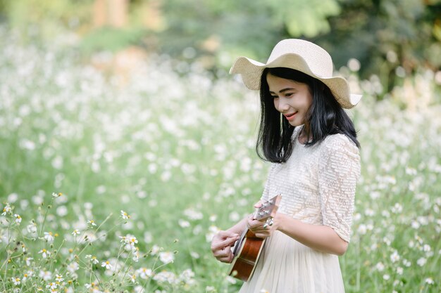 귀여운 하얀 드레스를 입고 우쿨렐레를 연주하는 여자