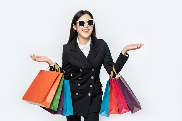 The woman wearing dark clothes and glasses, along with many bags, to go shopping