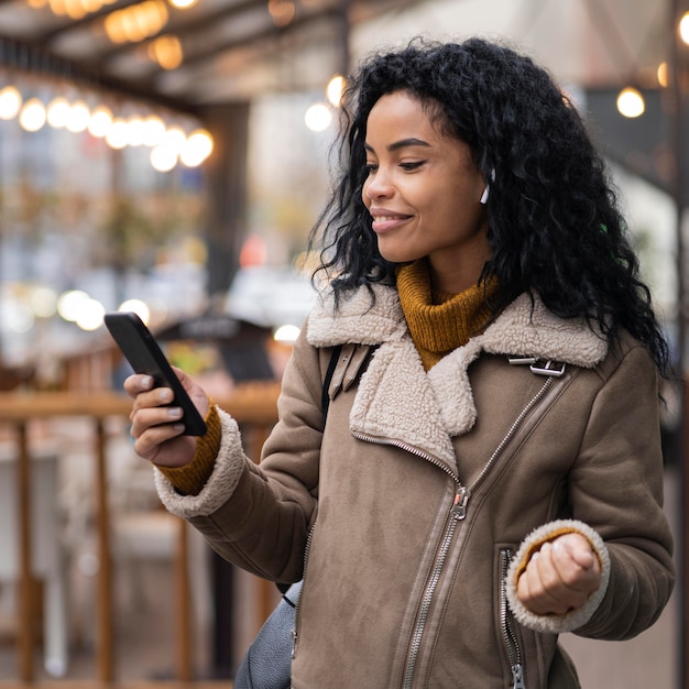 Free photo woman wearing earbuds to listen to music outside