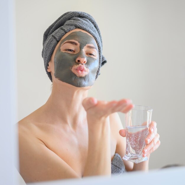 鏡にキスを吹くフェイスマスクを着ている女性
