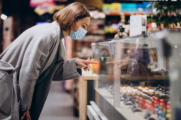 Женщина в маске для лица и покупки в продуктовом магазине