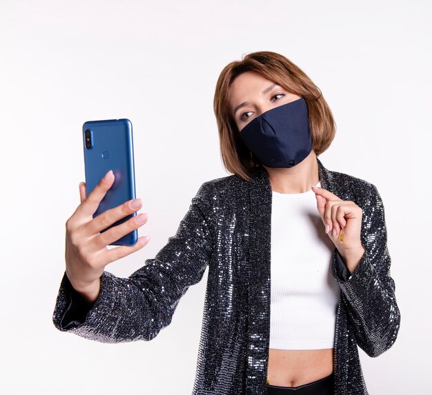 自撮り写真を撮るフェイスマスクを身に着けている女性