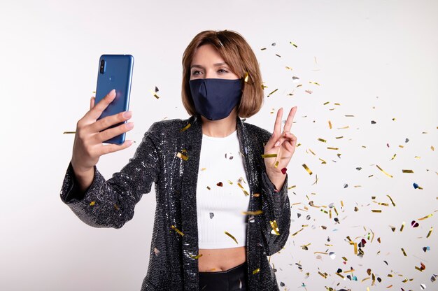 Foto gratuita donna che indossa la maschera per il viso prendendo un selfie