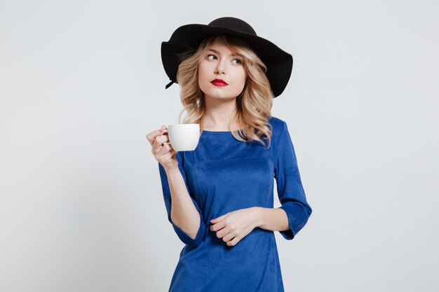Шляпа женщины нося держа чашку кофе