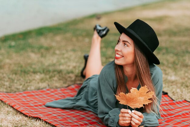 Woman wearing a hat while staying on a blanket