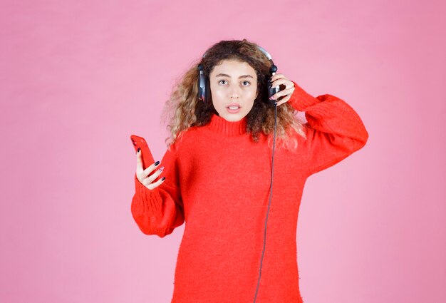 woman wearing headphones listening to her playlist at smartphone and looks dissatisfied.