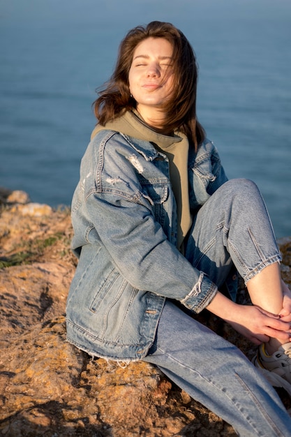Woman wearing jeans jacket alongside ocean
