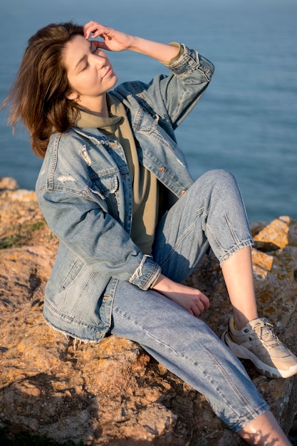 Free photo woman wearing jeans jacket alongside sea
