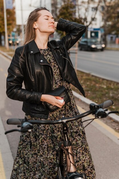 Woman wearing a long dress holding her bike front view