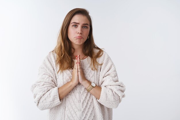 женщина в свободном свитере короткая стрижка поджимая подбородок ныть с просьбой о помощи скажите пожалуйста, сложите ладони вместе жест молитвы с надеждой