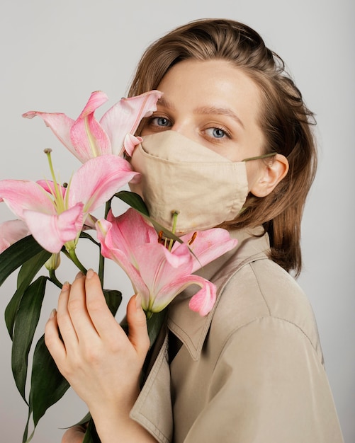 Foto gratuita donna che indossa una maschera e azienda bouquet di fiori